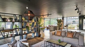 Un salon moderne avec une grande fenêtre, un canapé, une table basse et une bibliothèque.
