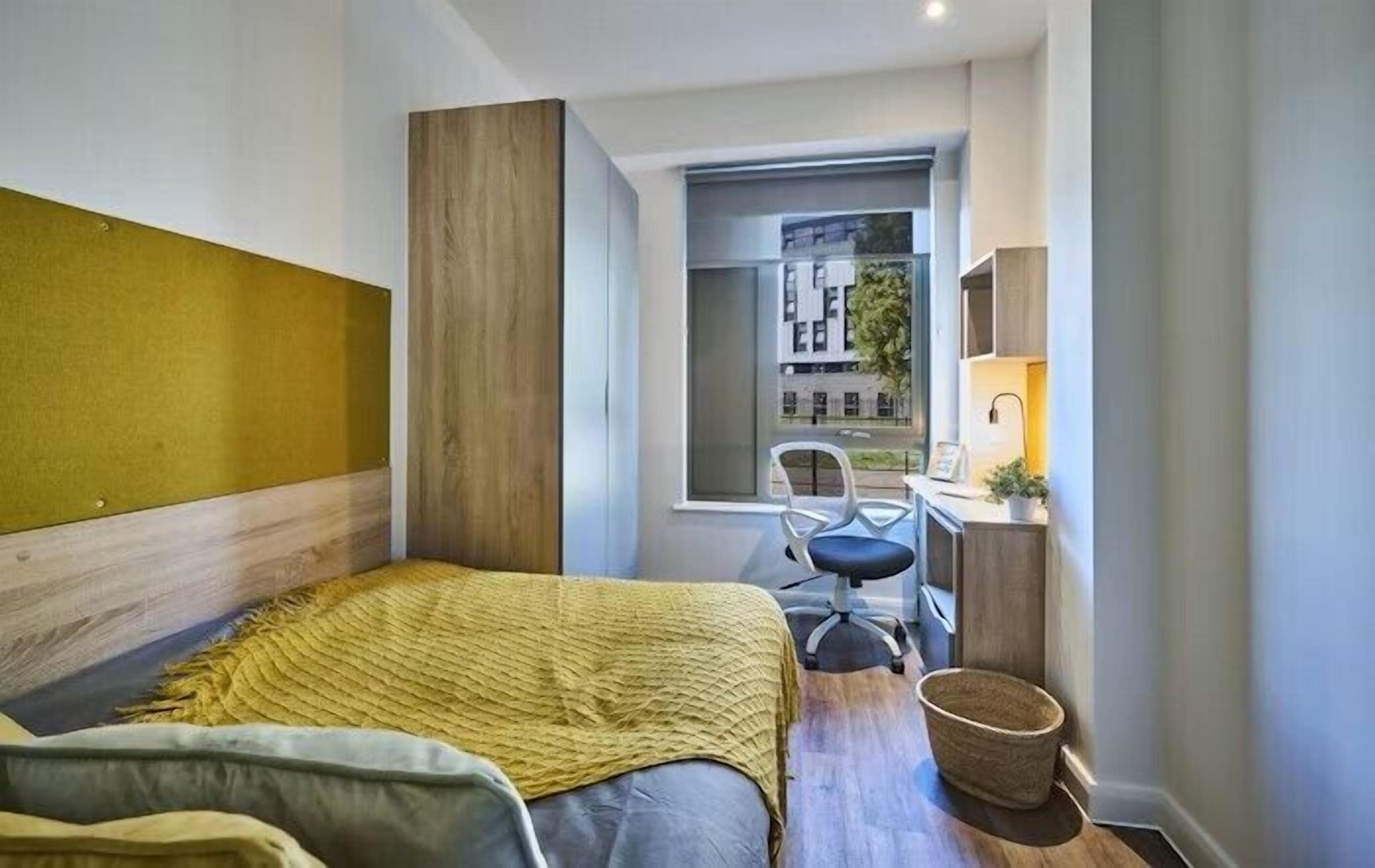 Habitación de hotel pequeña con cama, escritorio y silla.