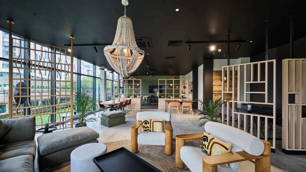 Un intérieur moderne agrémenté d’un grand lustre, de meubles en bois et offrant une vue dégagée grâce à de larges fenêtres.