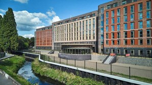 Un bâtiment moderne à étages, doté d’une cour intérieure et d’un canal d’eau qui le longe.