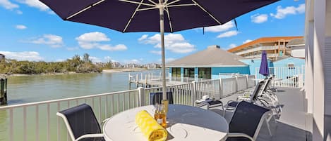 A balcony with a table, chairs, and a large umbrella.
