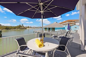 A balcony with a table, chairs, and a large umbrella. - Coastal waterfront condo located in Olde Marco (Marco Island)