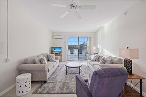 A modern living room with two sofas, a coffee table, and a TV. - Coastal waterfront condo located in Olde Marco (Marco Island)
