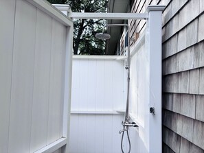 A white wooden structure with a showerhead and hose, likely a shower enclosure.