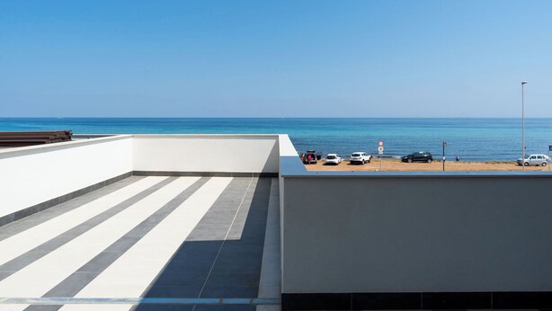 Une terrasse sur le toit offrant une vue dégagée sur la mer, un espace de stationnement et un lampadaire.