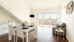 Un salon moderne comprenant un coin repas, un escalier et une grande fenêtre donnant sur la ville.