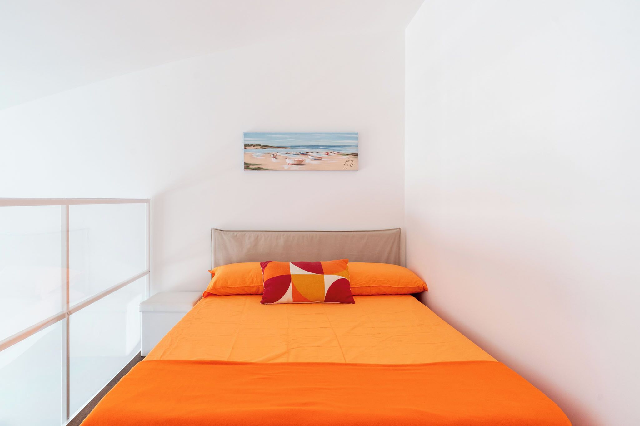 Una camera da letto moderna con un letto, un quadro raffigurante una spiaggia e un'ampia finestra.