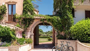 A covered outdoor area with a brick archway, a tiled floor, and two bicycles parked.