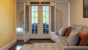 Una sala de estar con un sofá seccional color beige, un tapete estampado y una puerta que da a un espacio al aire libre.