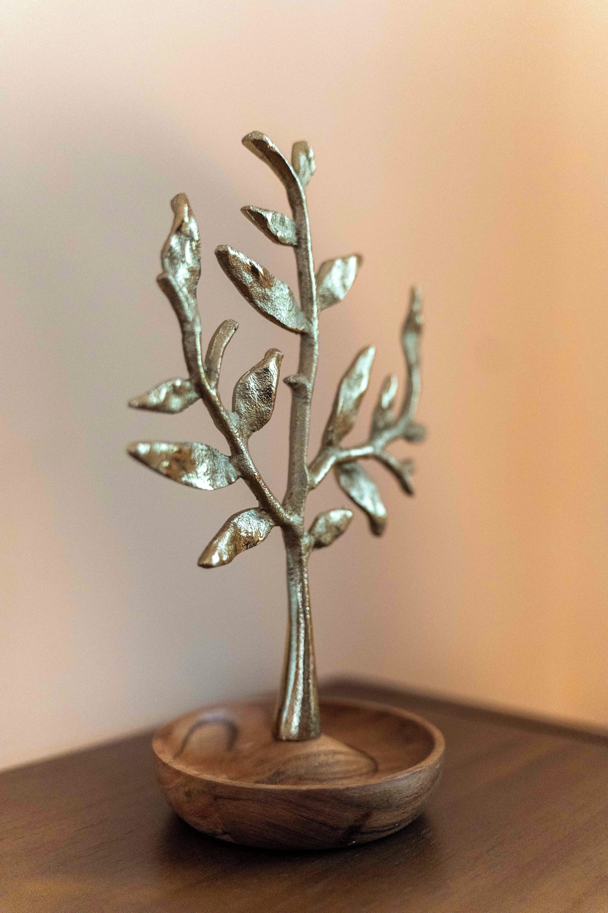 Une sculpture représentant un arbre, faite de métal, montée sur un socle en bois.
