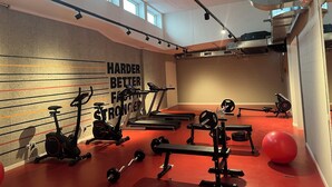 Een sportschool met trainingsapparatuur, motiverende tekst op de muur en grote ramen.