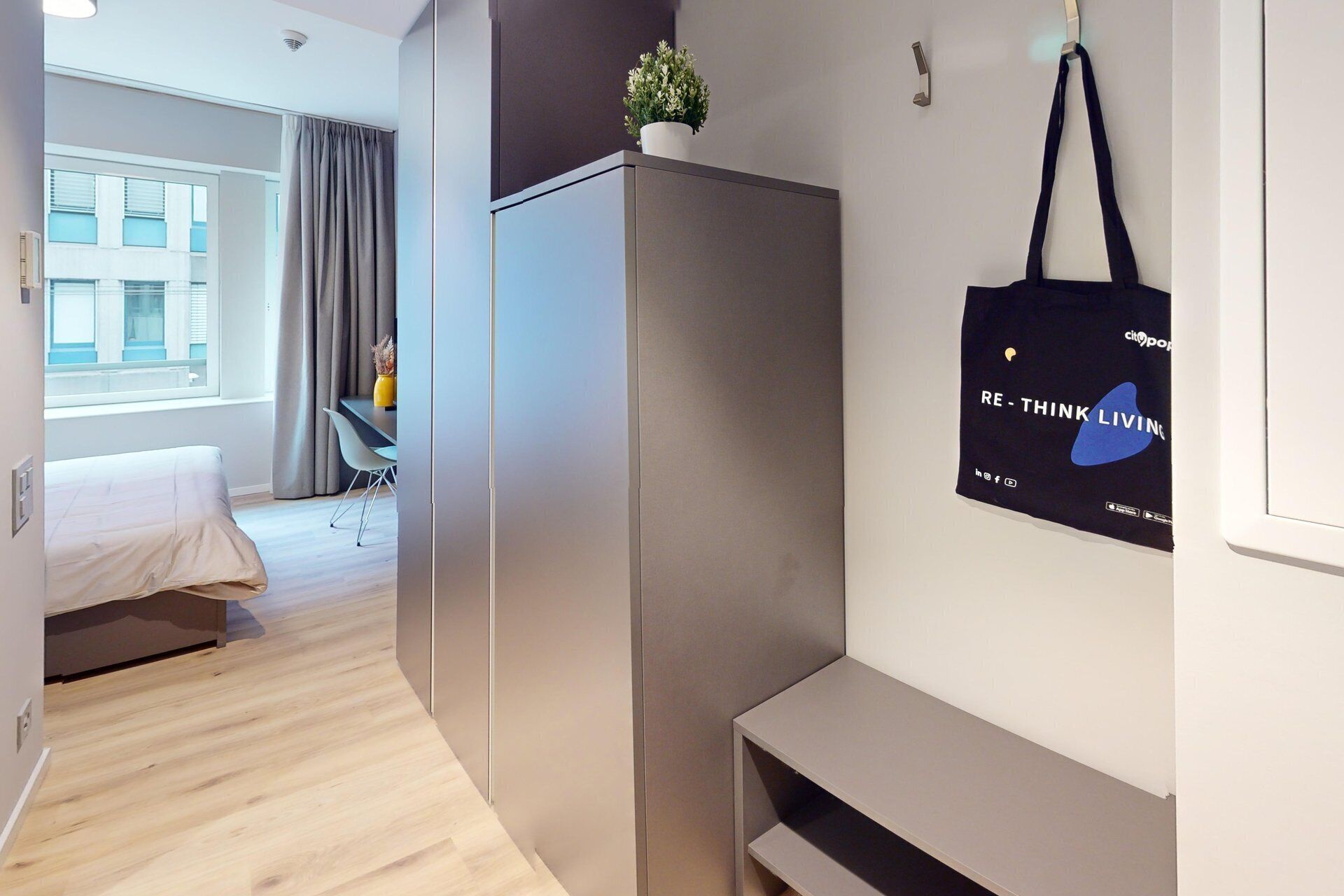 Quarto de hotel moderno com uma cama, uma escrivaninha e um guarda-roupa.