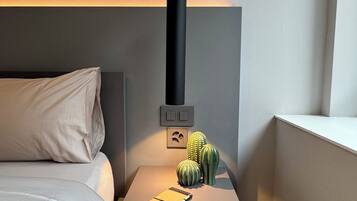 A modern bedroom with a bed, bedside table, and a hanging light fixture.