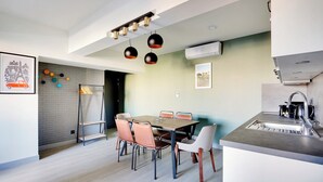 Una cocina moderna con zona de comedor, que incluye una mesa de madera, sillas y un lavamanos empotrado.