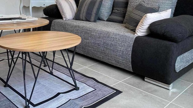 Una sala moderna con un sofá, una mesita de centro y una lámpara. Cuenta con una cocina con armarios y un microondas.
