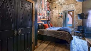 Una habitació amb un llit, una cadira, una televisió i un mural a la paret.