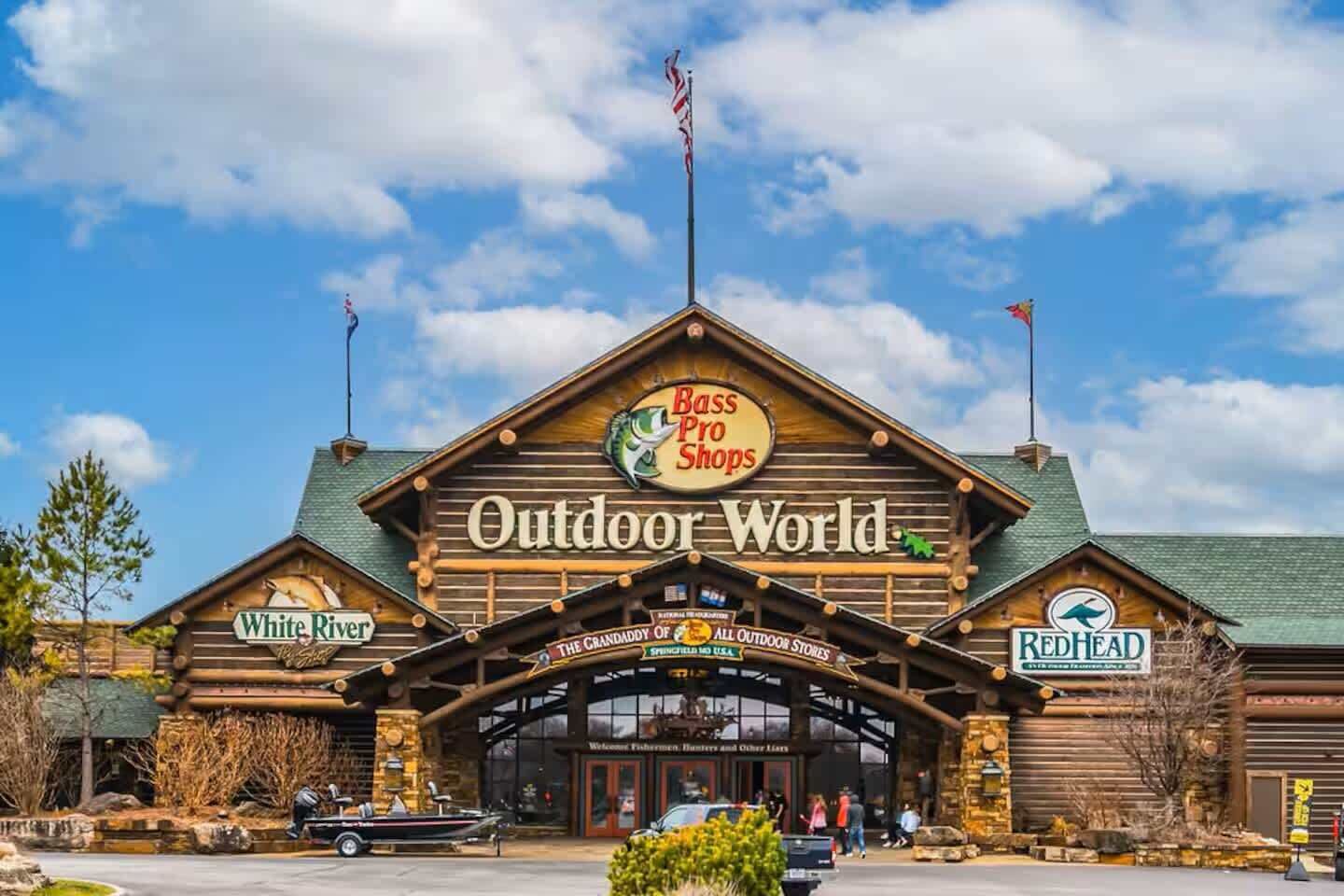 Un bâtiment de style cabane en rondins, avec des enseignes indiquant « Bass Pro Shops », « White River » et « Redhead ».