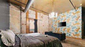 A bedroom with a bed, a TV, and a patterned wall. - Welcome to Black Palace-D! A beautiful downtown loft with easy access to everyth (Springfield)