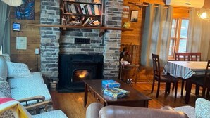A cozy living room with a stone fireplace, a bookshelf, and a dining area with wooden furniture. - Relax at this peaceful place w/kayaks and dock available for personal boats (Weston)