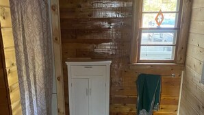 A wooden cabin interior with a white cabinet, a window with a view, and a green towel hanging by the window. - Relax at this peaceful place w/kayaks and dock available for personal boats (Weston)