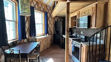 A spacious kitchen with wooden cabinets, a dining area with a table and chairs, and a staircase leading to an upper level.