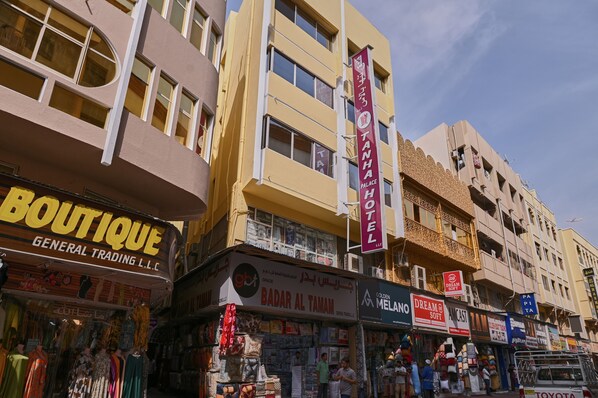 A hotel with a sign reading "TANHA PALACE HOTEL" and multiple shops on the ground floor. - Tanha Palace Hotel (Dubai)