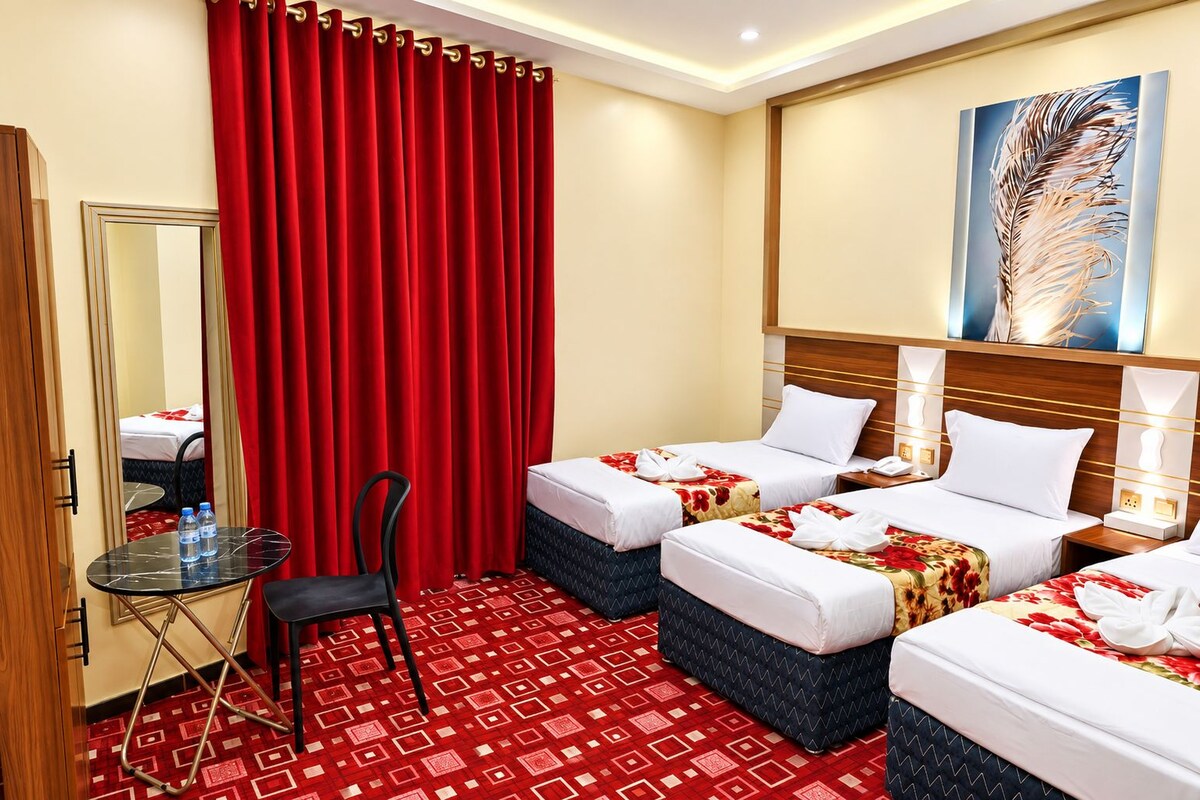A hotel room with two beds, a chair, a small table, and a mirror.