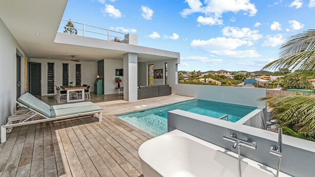 Ein moderner Poolbereich im Freien mit Liegestuhl, Whirlpool und Essbereich mit Tisch und Stühlen.