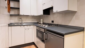 A modern kitchen with white cabinets, a stainless steel refrigerator, a gas stove, and a built-in oven. - Suite Carla Cozy Apartment in Petrasanta Center (Pietrasanta)