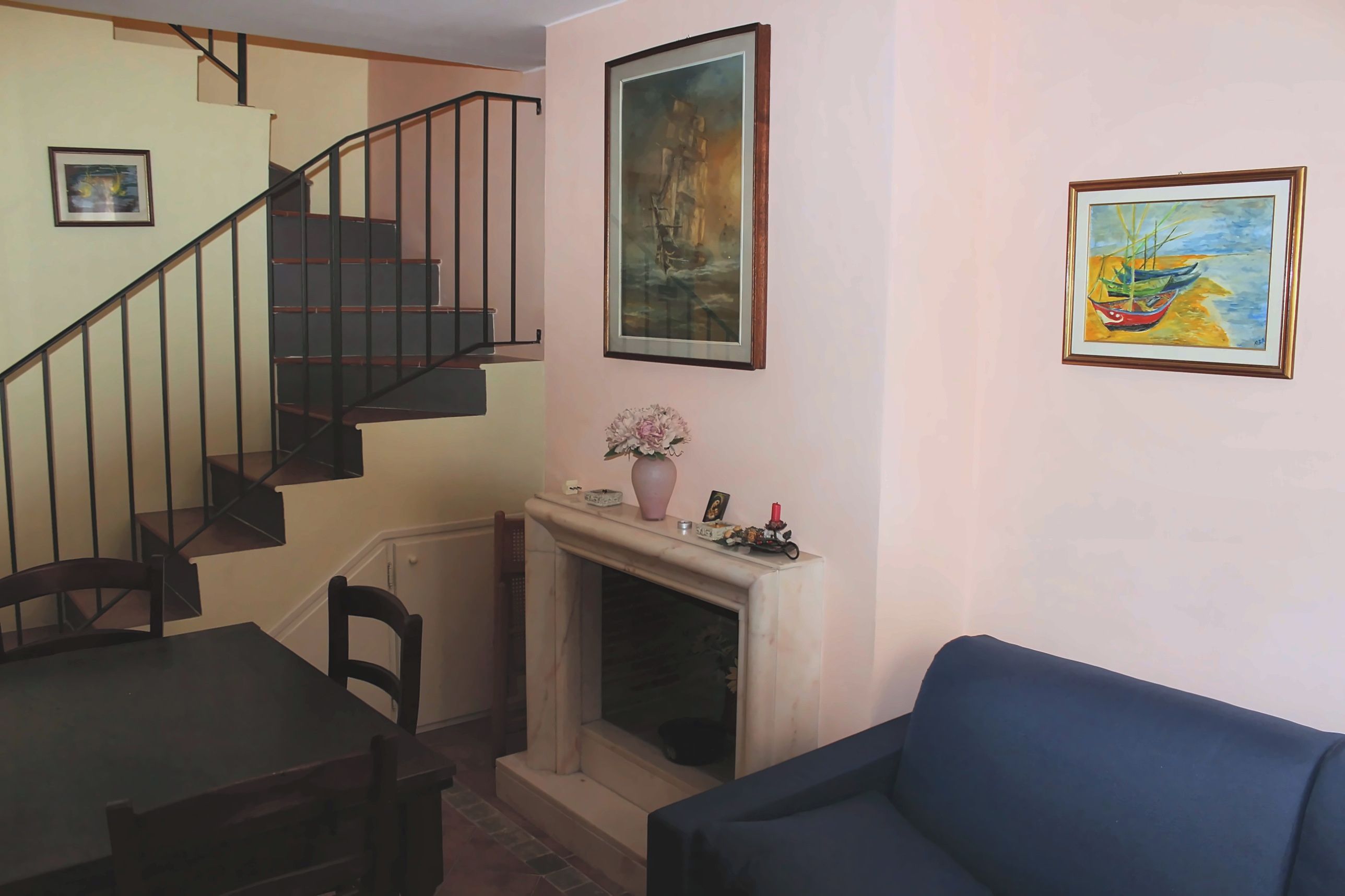 A living room with a fireplace, a staircase, and a dining area.