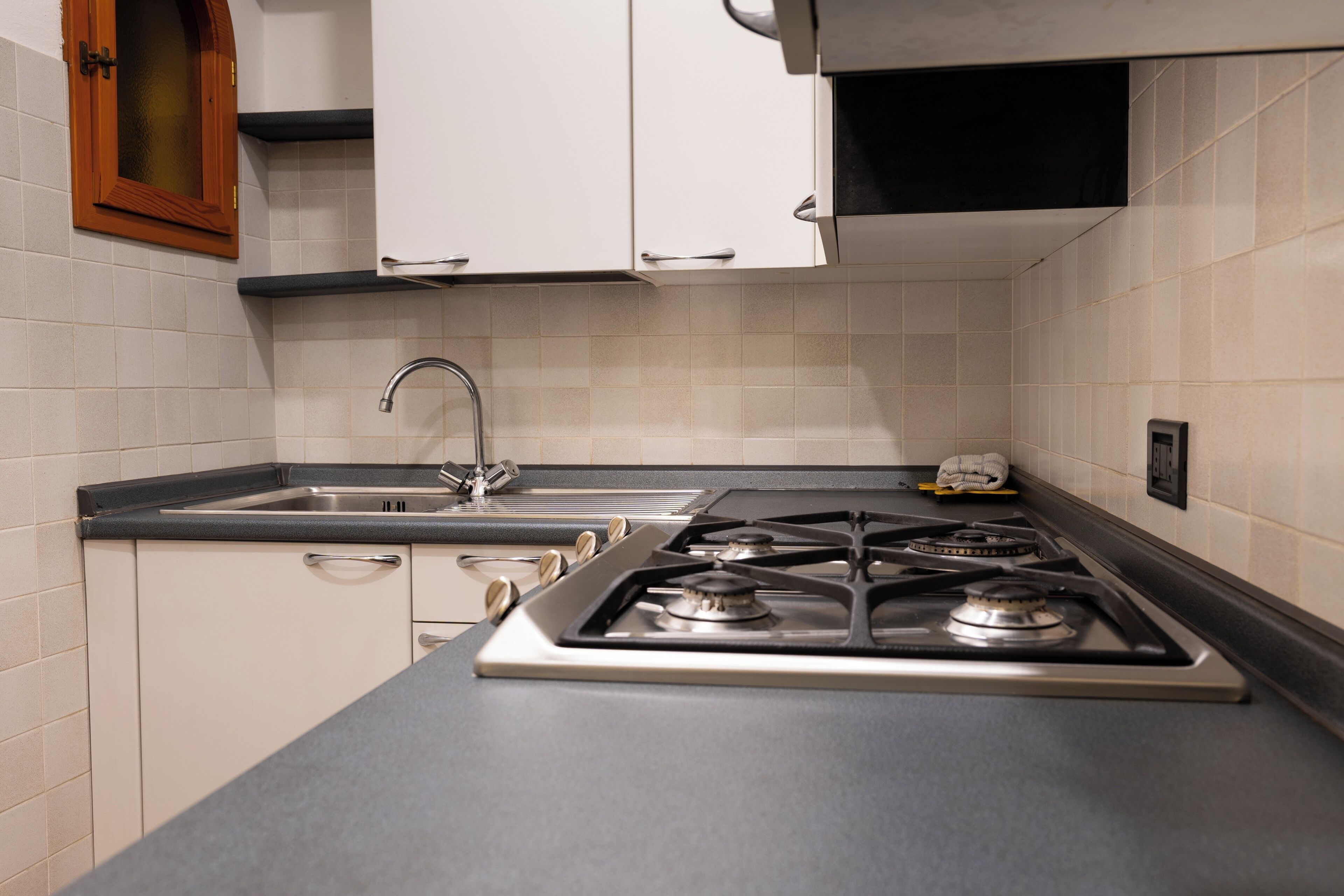 A kitchen with white cabinets, a stainless steel sink, and a gas stove.