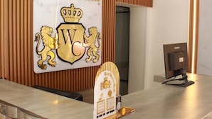 A reception desk at Hotel Windsor Castle with a sign displaying the hotel name and logo. - Hotel Windsor Colombia (Bogotá)