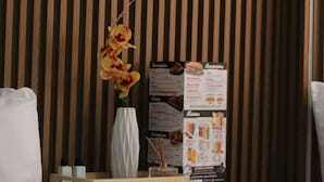 A wooden panel wall, a white vase with yellow orchids, a menu board, and a tray with bottles. - Hotel Windsor Colombia (Bogotá)