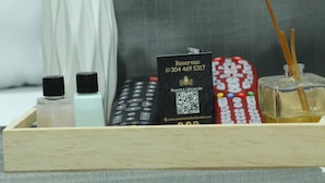 A wooden tray with a black card, a remote control, two bottles, and a glass bottle with a reed diffuser. - Hotel Windsor Colombia (Bogotá)