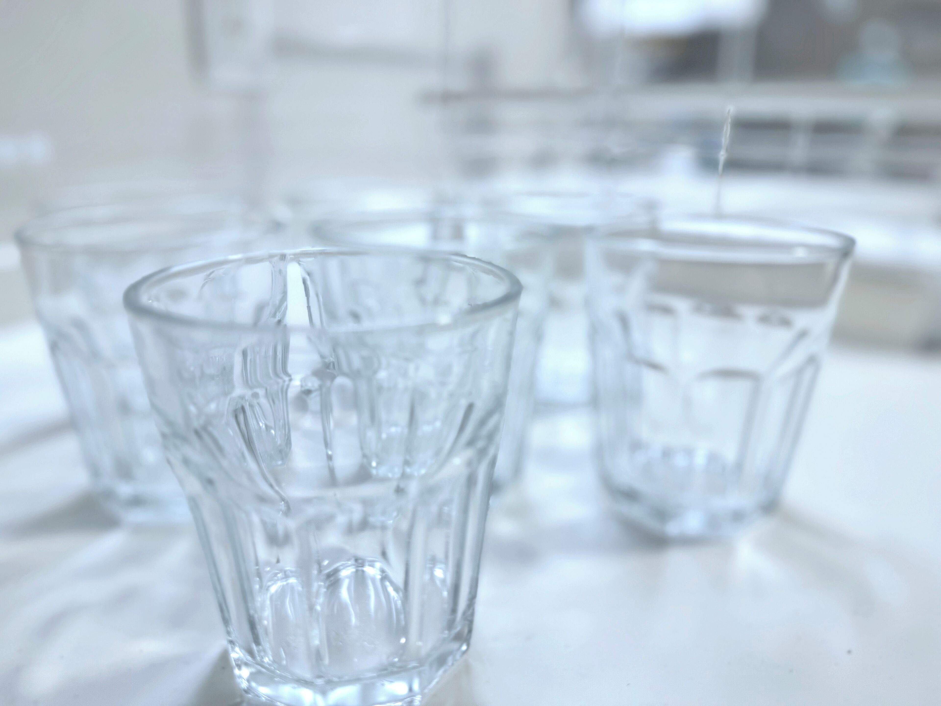 Un conjunto de vasos de vidrio transparentes y vacíos sobre una superficie blanca.