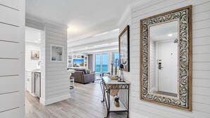 A spacious hallway with a wooden floor, a dining area with a table and chairs, and a large ornate mirror on the wall.