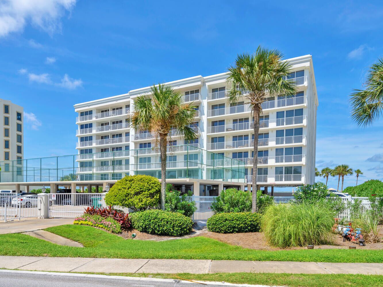 A multi-story hotel with balconies, surrounded by well-maintained landscaping and palm trees.