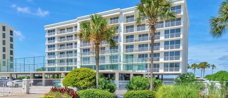 A multi-story hotel with balconies, surrounded by well-maintained landscaping and palm trees.