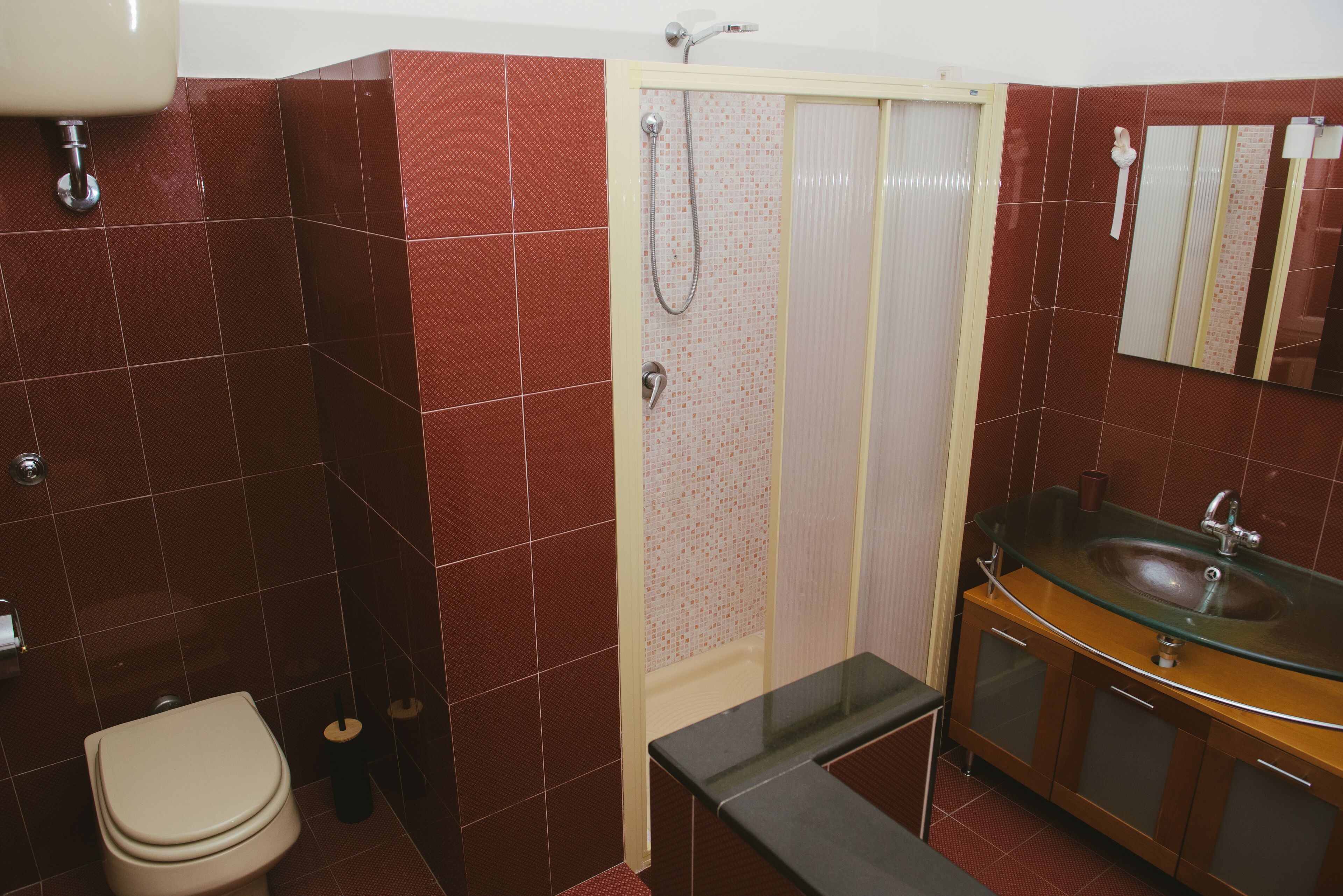 A bathroom with a toilet, a glass sink, and a shower enclosure.