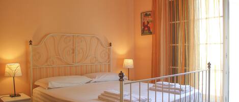 A neatly made bed with white linens, a metal headboard, and two bedside lamps.