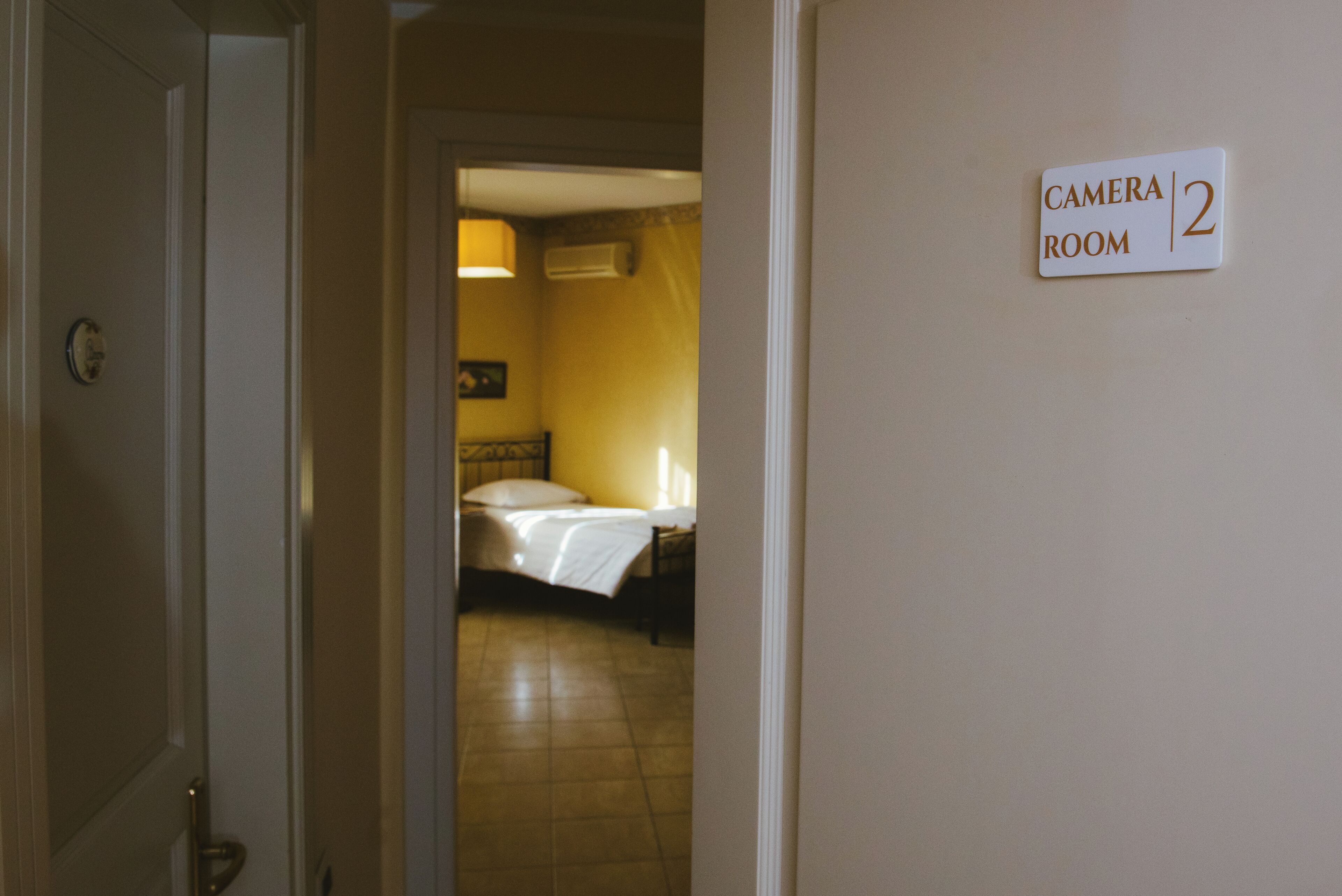 Ein Hotelzimmer mit Bett, Nachttisch und einem Schild, das angibt, dass es sich um das Kamera-Zimmer 2 handelt.