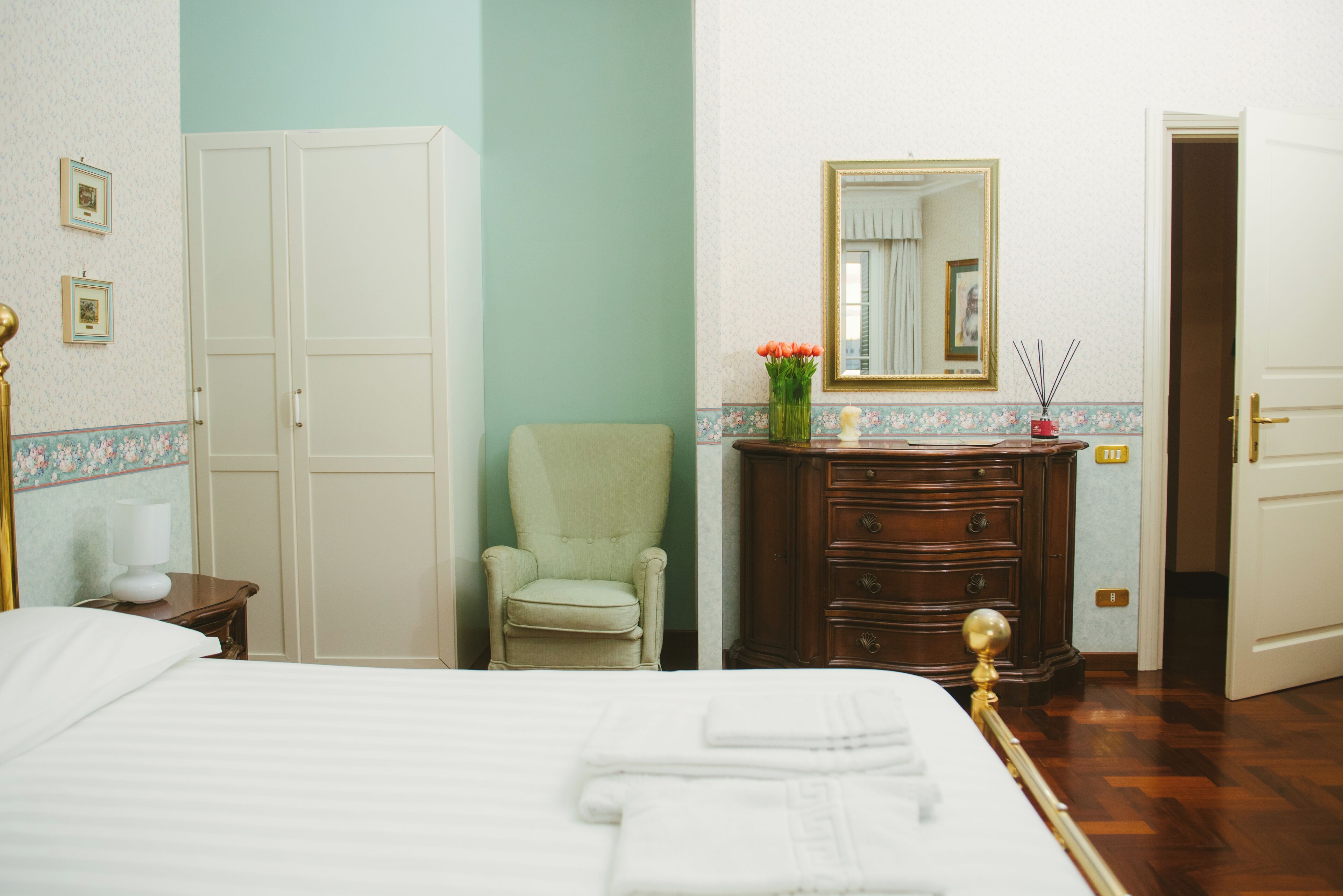 A hotel room with a bed, a chair, a dresser, and a mirror.