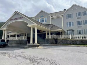 A Country Inn with a covered entrance, stone facade, and a white fence.