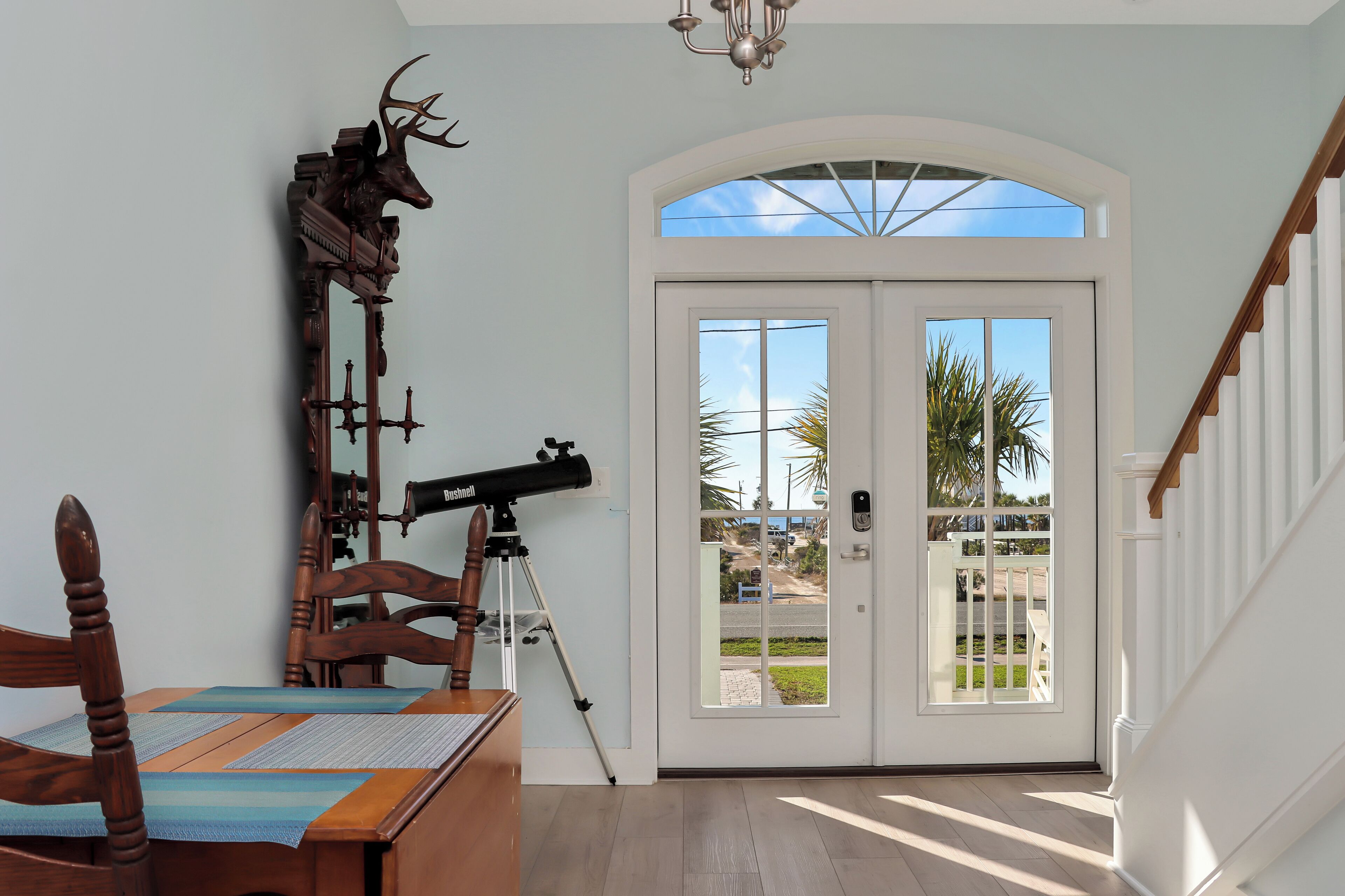 A dining area with a wooden table, chairs, a telescope, and a deer head decoration.
