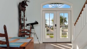 A dining area with a wooden table, chairs, a telescope, and a deer head decoration. - 🌊Dog Friendly Home with Private Pool-Steps to the Beach-Salty Owl🌊 (Cape San Blas)