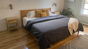 A bedroom with a wooden bed, two bedside tables, a window, and a plant. - Spacious Charming Kennebunk Home (Kennebunk)