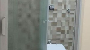 Kylpyhuone, jossa on lasiseinällä varustettu suihku, wc ja laatoitettu seinä.