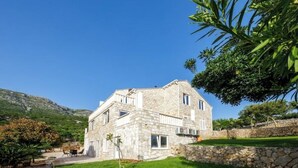 A stone building with a sloped roof, a paved driveway, and a well-maintained lawn. - Apartments Mi&Ni -Comfort Two Bedroom Apartment with Terrace and Sea View (no.3) (Cavtat)