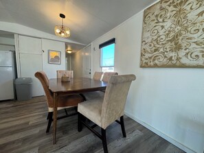 Un coin repas avec une table en bois et des chaises rembourrées, un luminaire suspendu et un élément décoratif mural.
