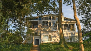 A two-story house with a front entrance, a staircase leading up to the door, and a large window on the second floor.